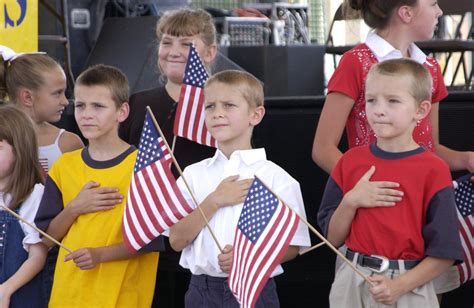 Students with hand over heart reciting the Pledge in front of the U.S. flag